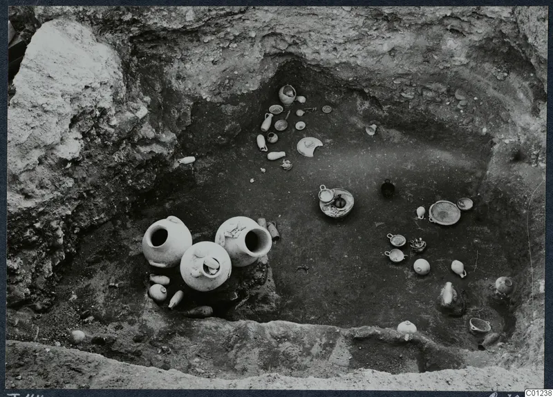 Tomb 44 at Marion during excavation, with pottery vessels and small objects lying on the floor of the cut.