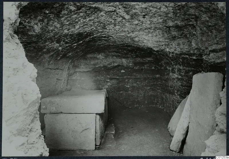 Interior of Tomb 34 at Marion, a rock-cut chamber with a stone sarcophagus under a flat slab lid.