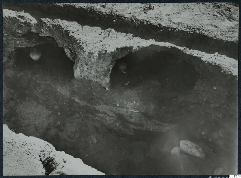 Tomb 31 at Marion during excavation, with two vessels in hollows in the cut wall and stones on the floor