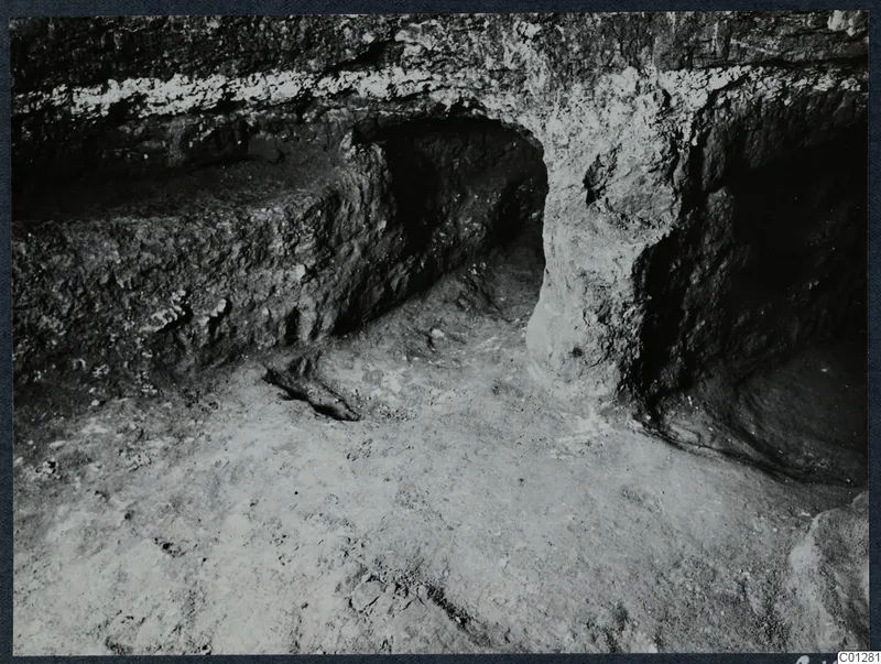 Interior of Tomb 39 at Marion during excavation, showing a rock-cut opening and a ledge along the wall.