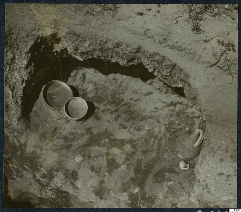 Tomb 31 at Marion during excavation, with two round vessels and a partly exposed vessel in the cut
