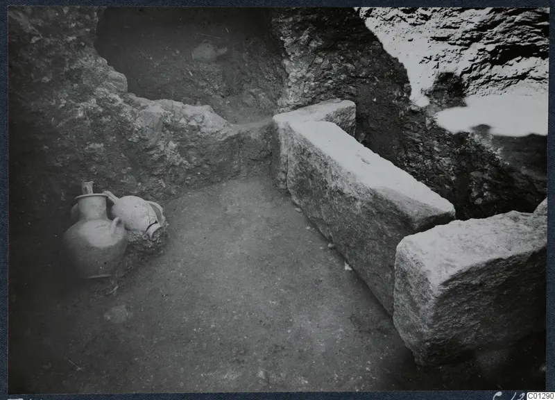 Tomb 41 at Marion: interior of a tomb chamber with cut stone blocks and two vessels against the wall