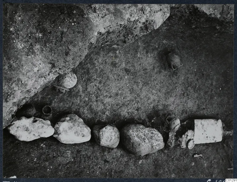 Tomb 41 at Marion: a row of stones and small vessels on an excavated floor