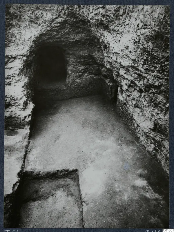 Tomb 61 at Marion during excavation, looking along a rock-cut passage toward a dark opening at the far end.