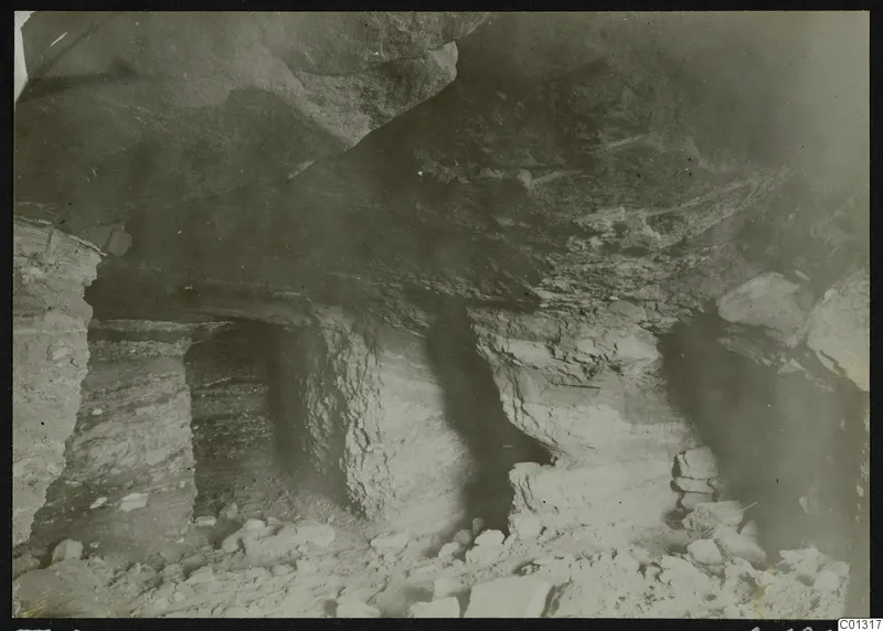 Interior of Tomb 2 at Marion, showing rock-cut walls, a low ceiling and stones scattered across the floor.