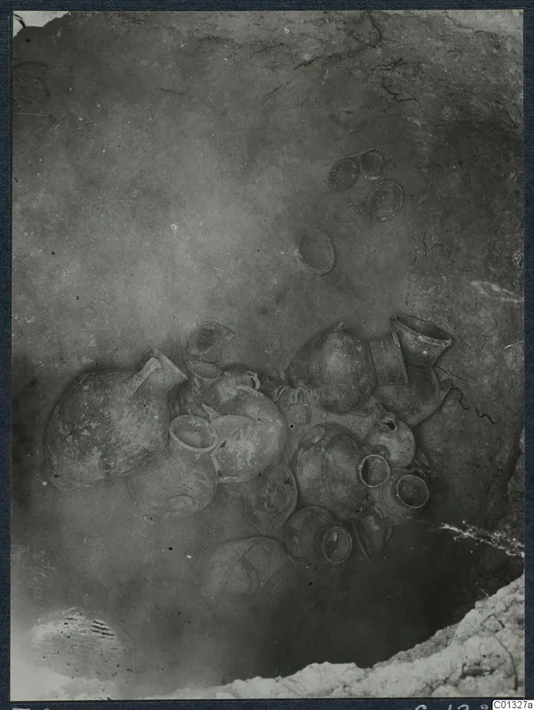 Pottery vessels clustered on the floor of Tomb 95 at Marion, photographed in situ.