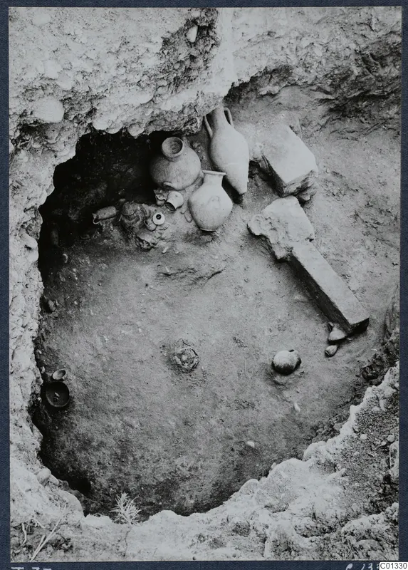 Tomb 73 at Marion during excavation, with pottery vessels and stone slabs lying in situ.