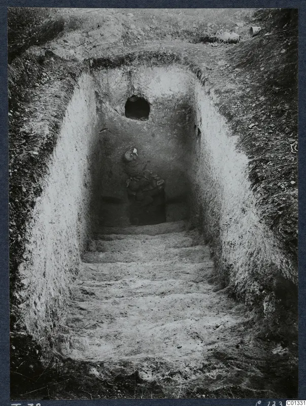 Tomb 72 at Marion: a sloping dromos with steps leading down to a tomb chamber containing objects