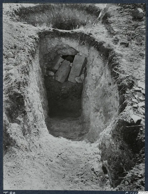 Excavation of Tomb T.88 at Marion, with flat stone slabs over an opening at the bottom of the cut