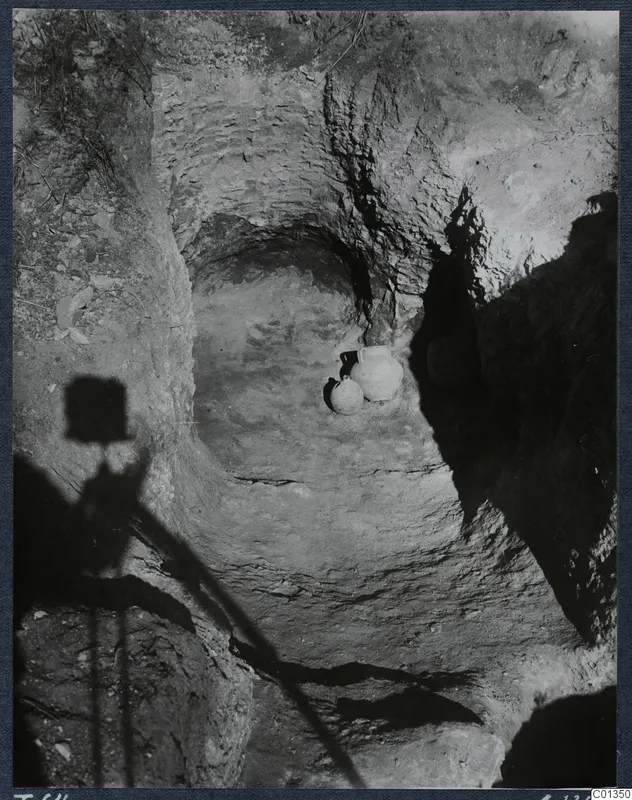 Tomb 64 at Marion during excavation, with two jars resting on the cut floor of the rock-cut chamber.