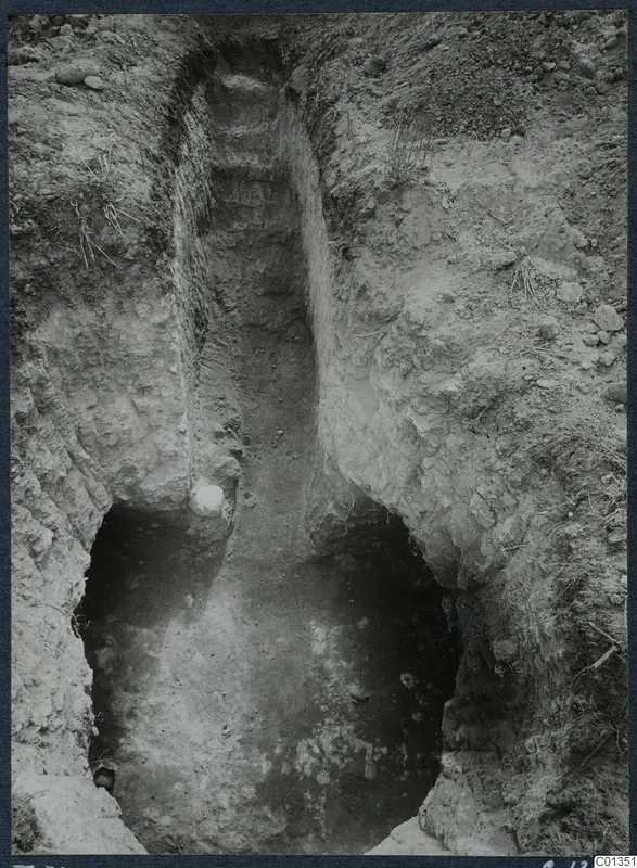 Tomb 70 at Marion during excavation: a stepped passage cut down into pale soil, opening to a dark tomb chamber.