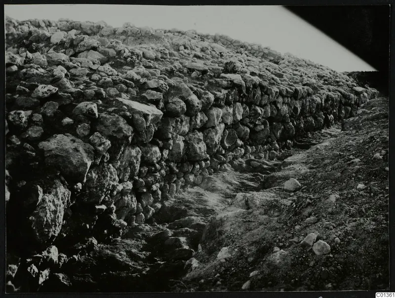 Rough stone wall at Nitovikla, with an excavated path or cutting running along its foot.