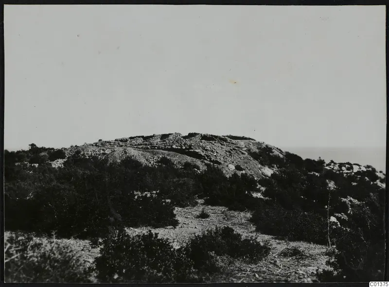Low rocky hill with scrub and stone walling along its crest, with the sea visible beyond at Nitovikla, Karpas peninsula.