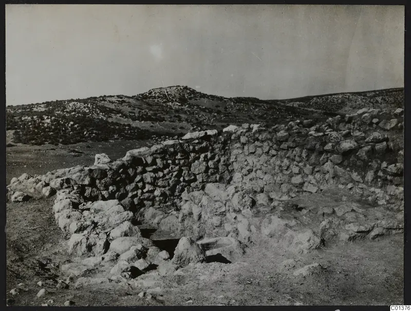 Stone wall and rubble with a rocky hill behind, at Nitovikla on the Karpas Peninsula