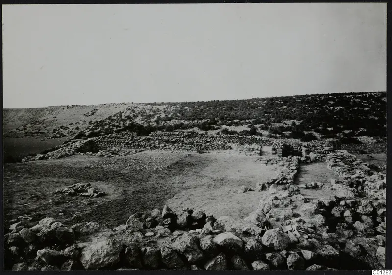 Stone walls and foundations at Nitovikla on the Karpas Peninsula, with scrubby hills rising behind.
