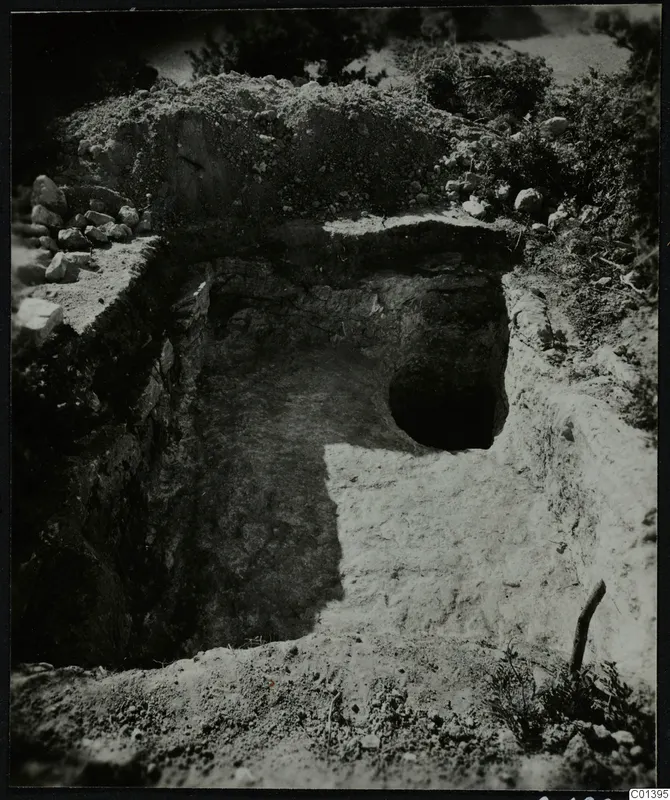Excavation cutting at Nitovikla on the Karpas Peninsula, with a round dark opening in the far wall