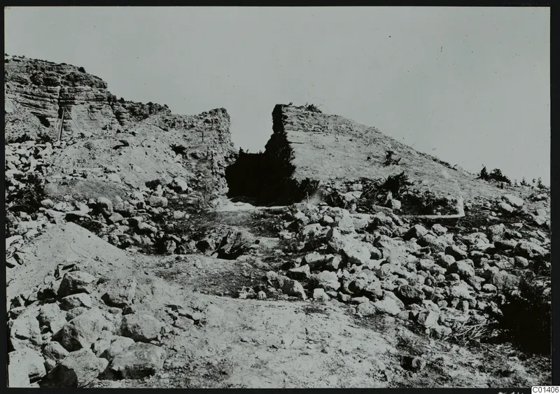 Excavated rocky hillside at Nitovikla with a dark opening in a cut rock face and scattered stones