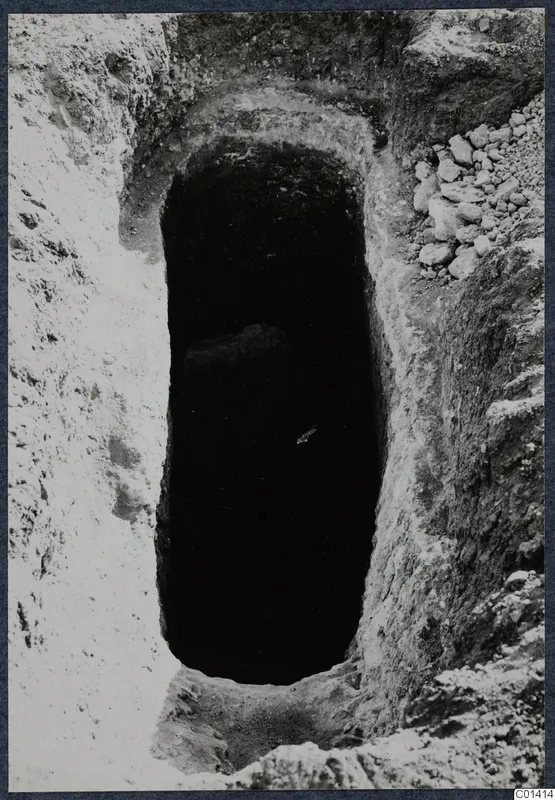 Tomb 13 at Ayios Iakovos during excavation, seen from above as a dark rectangular opening in pale soil