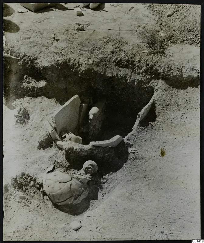 Excavated pit at Ayios Iakovos with a broken pottery jar, standing stone slabs and skulls in the soil