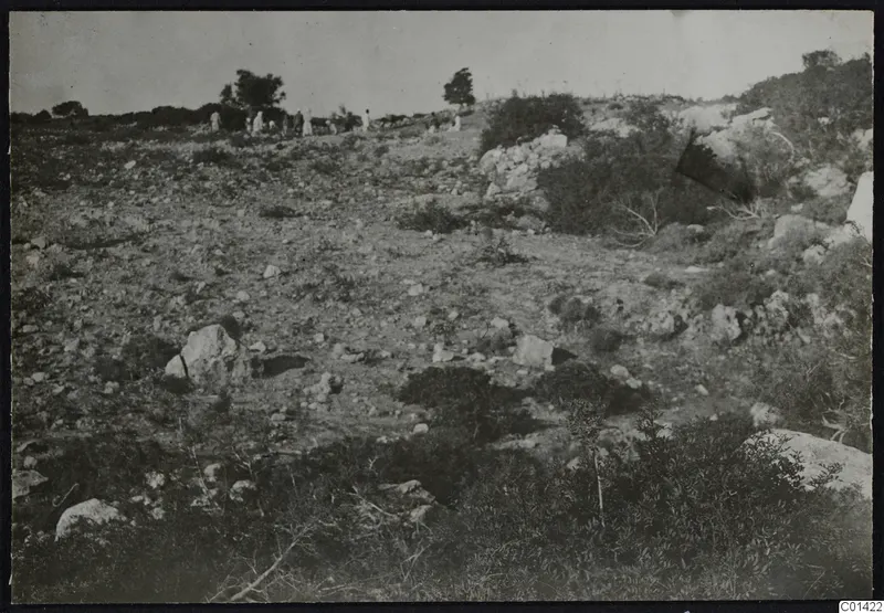 Rocky hillside with scrub and a group of people standing on the ridge at Nitovikla