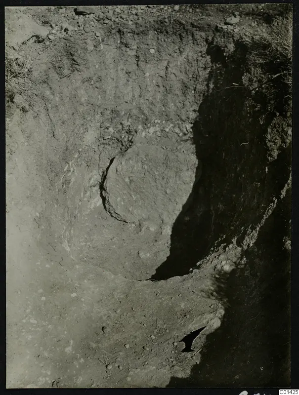 Excavation cutting at Kountoura Trachonia with a curved soil face, dark shadowed walls and scattered stones