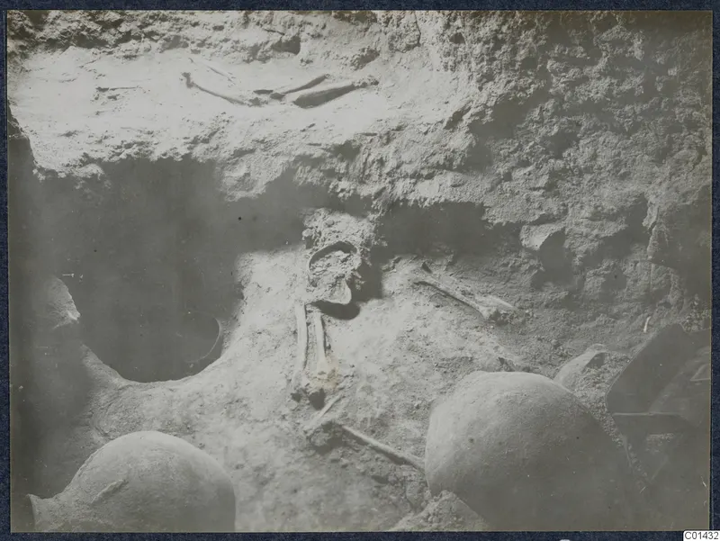Tomb chamber at Ayios Iakovos during excavation, with bones and rounded objects set in the soil