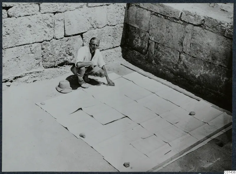 John Lindros kneeling beside the large plan of the Vouni palace, pieced together from paper sheets on the ground.