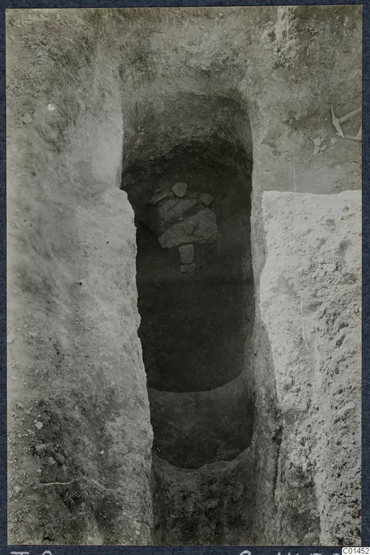 Tomb 8 at Ayios Iakovos during excavation, with stone slabs in the chamber opening and a pick at the top right