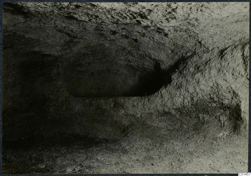 Interior of Tomb 14 at Ayios Iakovos, a rock-cut chamber with rough walls and loose debris on the floor.