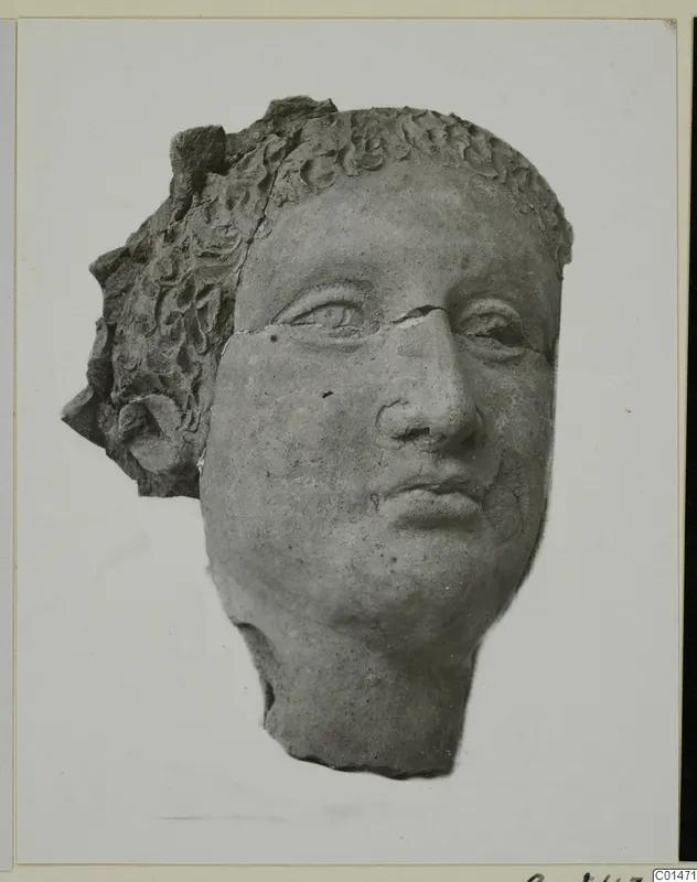 Head fragment of a statue with curled hair in relief and a broken nose, shown on a mounted card