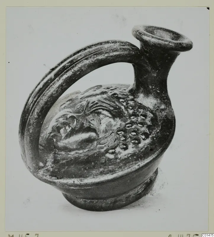 Black glazed pottery vessel with a strap handle and raised relief decoration, from the Marion tombs 31–45 series