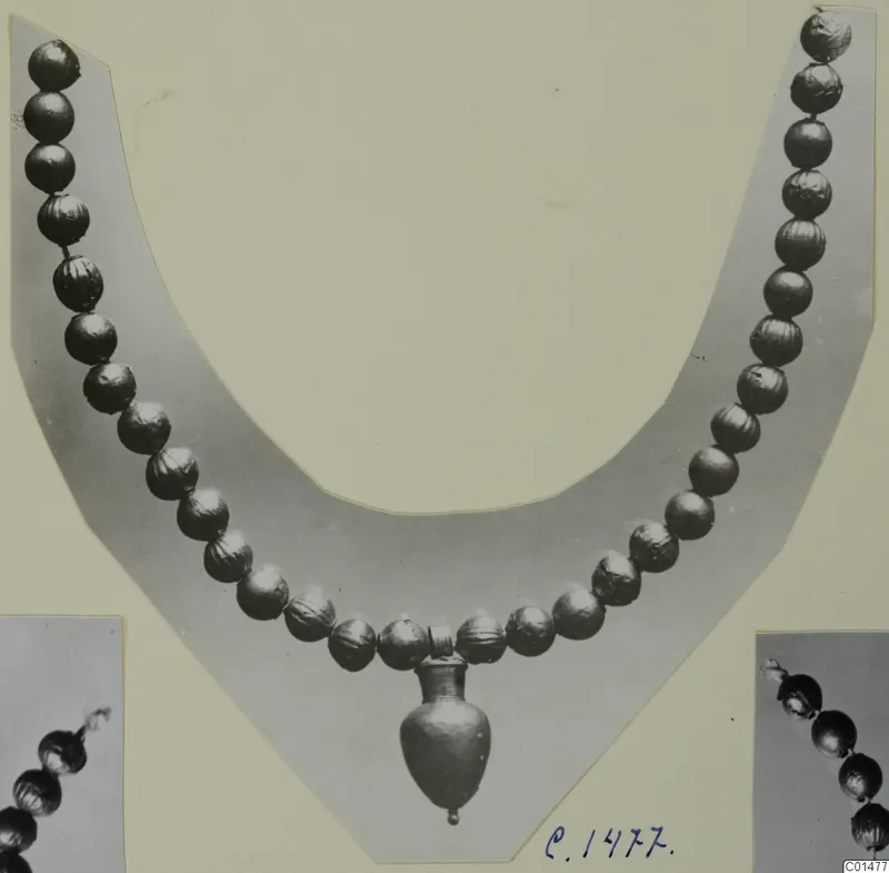 Necklace of metallic beads with a small vase-shaped pendant, shown on a card mount with two close-up views