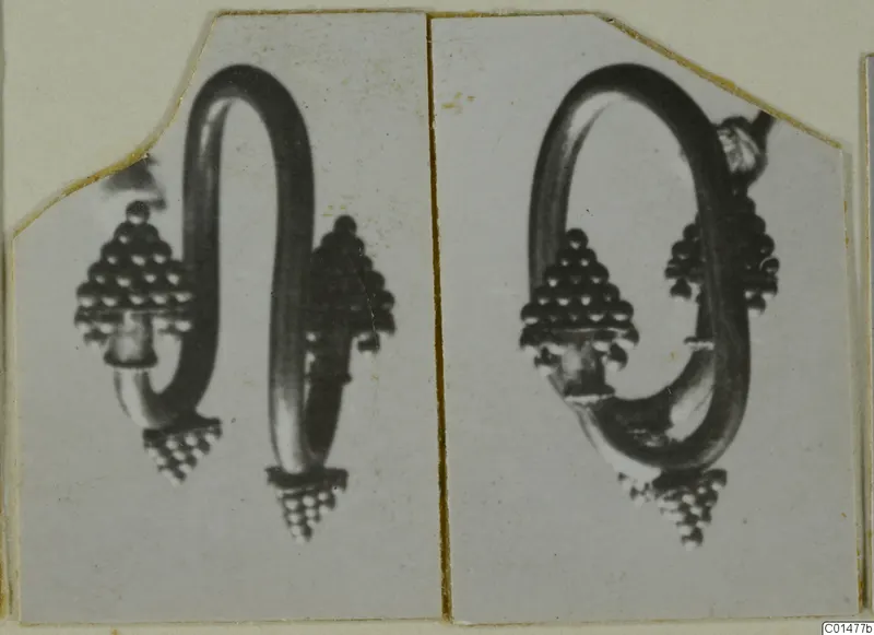 Two views of a gold earring with a looped wire and beaded cone-shaped ends, mounted side by side on a card