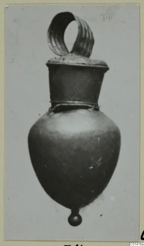 Gold pendant from Marion with a ribbed loop at the top and a small ball at the base