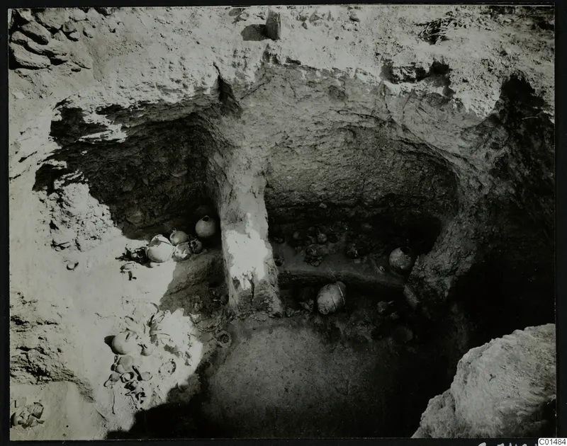 Rock-cut chamber at Nitovikla with pottery vessels and sherds lying on the floor during excavation.