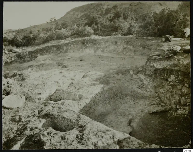 Excavation at Nitovikla on the Karpas Peninsula, with cut rock, a trench and digging tools on the ground