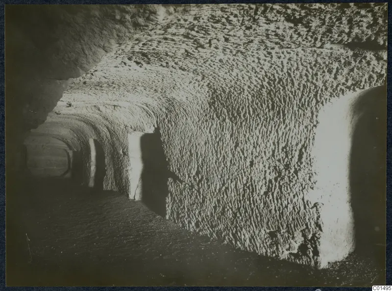 Interior of a rock-cut passage with a vaulted ceiling, chisel-marked walls and side openings, from the Karpas peninsula