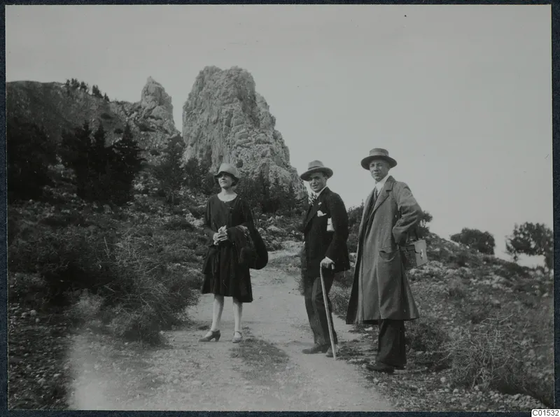 Three people standing on a dirt path below rocky crags at St. Hilarion.
