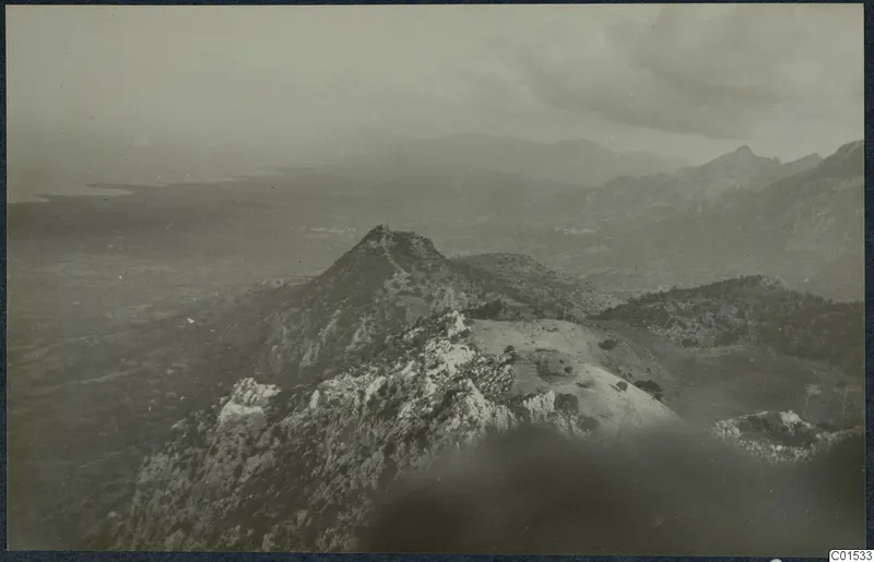 View over rocky hilltops and scrubby slopes in the Kyrenia Mountains, with a hazy plain and water on the left