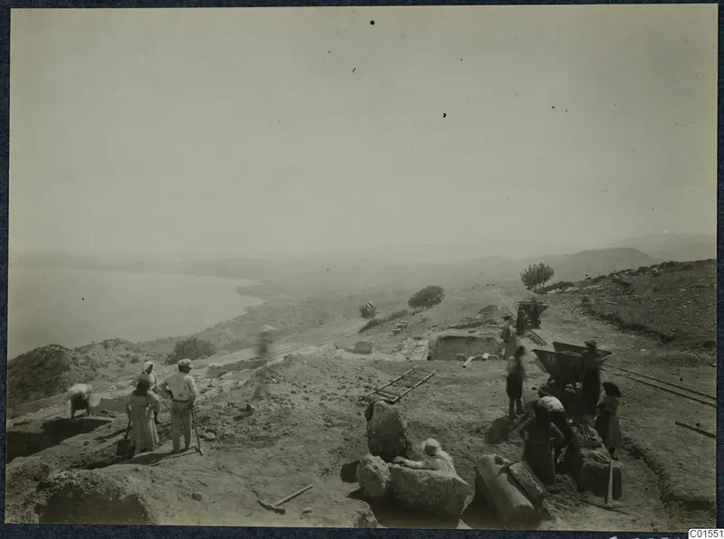 Workers on the excavation at Vouni above the sea, with rails, a wheelbarrow and a ladder lying on the ground