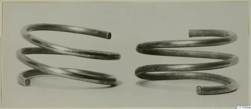 Two spiral silver armlets of round wire with open ends, shown side by side.