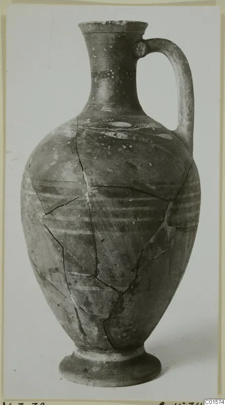 Pottery jug with a single loop handle and pale painted bands, with cracks across the body