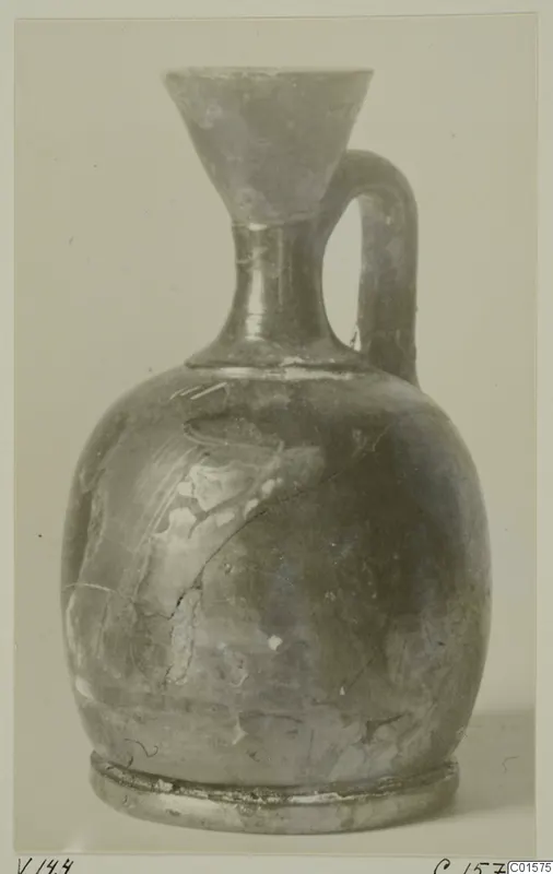 Pottery jug with a funnel mouth, a single loop handle and a ring foot, shown against a pale background