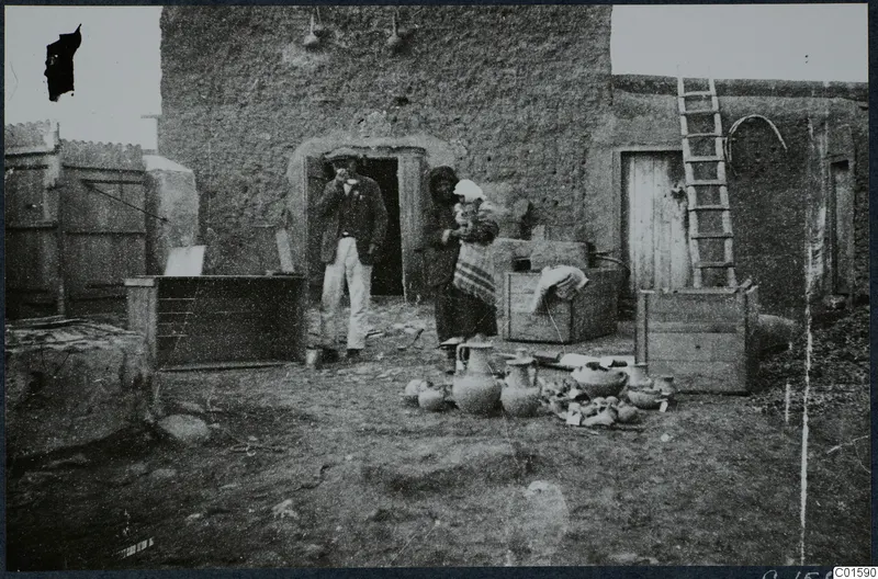 Packing pottery in a courtyard at Milia, with a man and a woman beside a mud-brick building