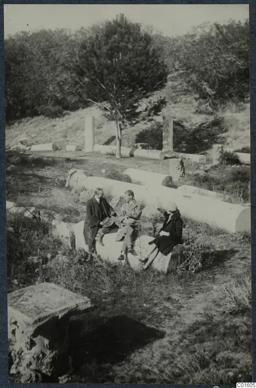 Three people sitting on a fallen column drum among scattered column fragments at Salamis, Famagusta.