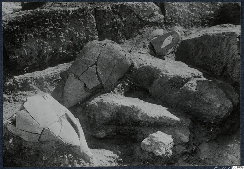 Broken pottery vessel and a loop handle lying in situ in an excavation at Vouni