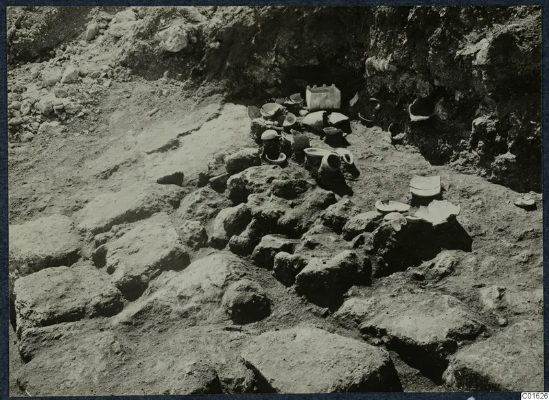 Pottery vessels lying in situ among large stone blocks during excavation at Vouni Palace