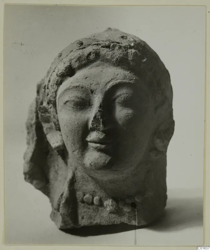 Terracotta head of a female figure with a beaded headdress and a row of beads at the neck, nose broken.