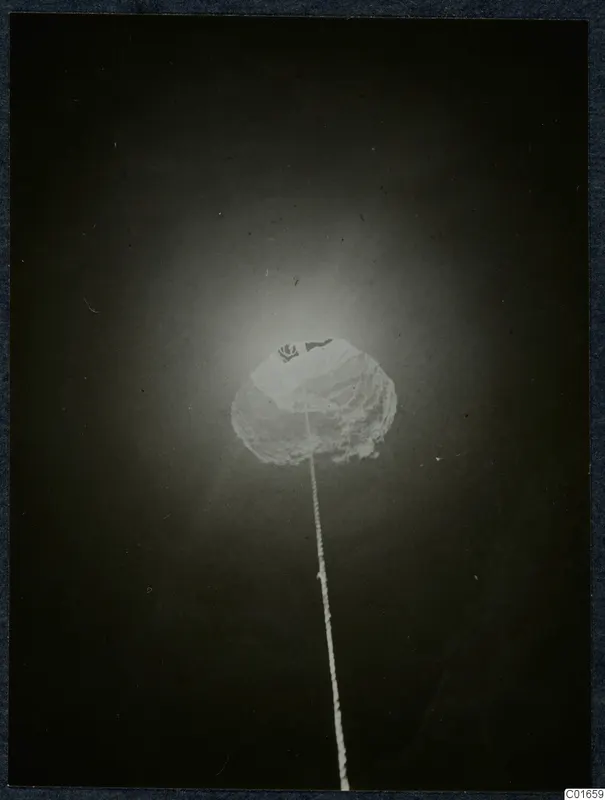 Glowing rounded light hanging on a long string against a very dark background