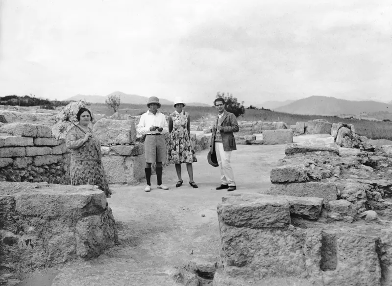 Four people standing among stone ruins at Vouni, with hills behind them.